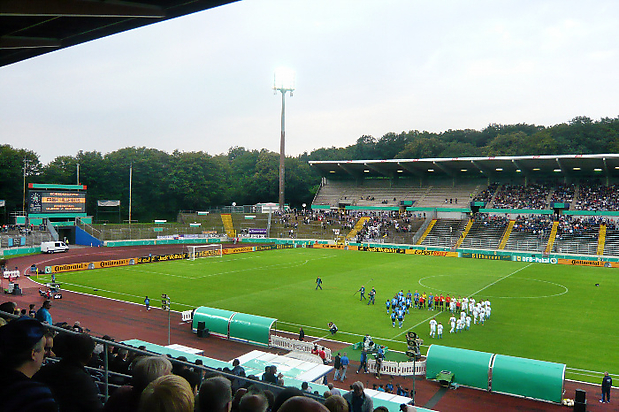 Einlauf der Mannschaften mit Gästeblock hinten